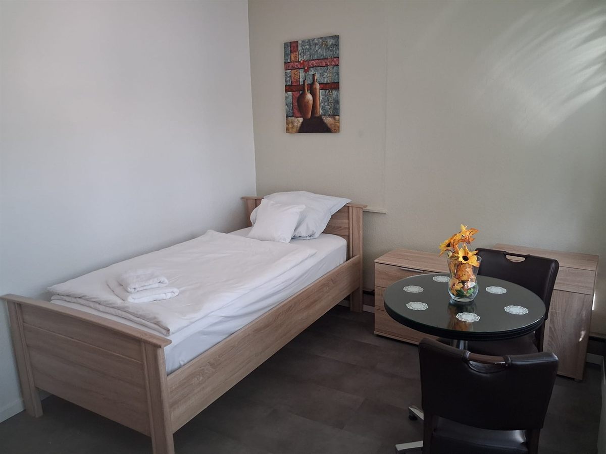 Einzelnes Monteurzimmer in der 2. Etage mit Bett, Ablage und Fernseher